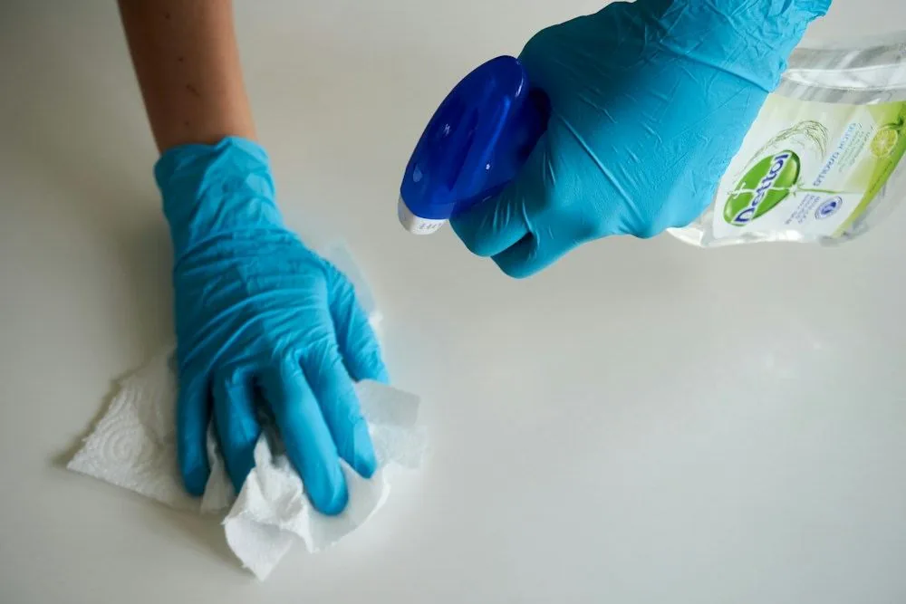 Gloved hands wiping an accessible kitchen work surface